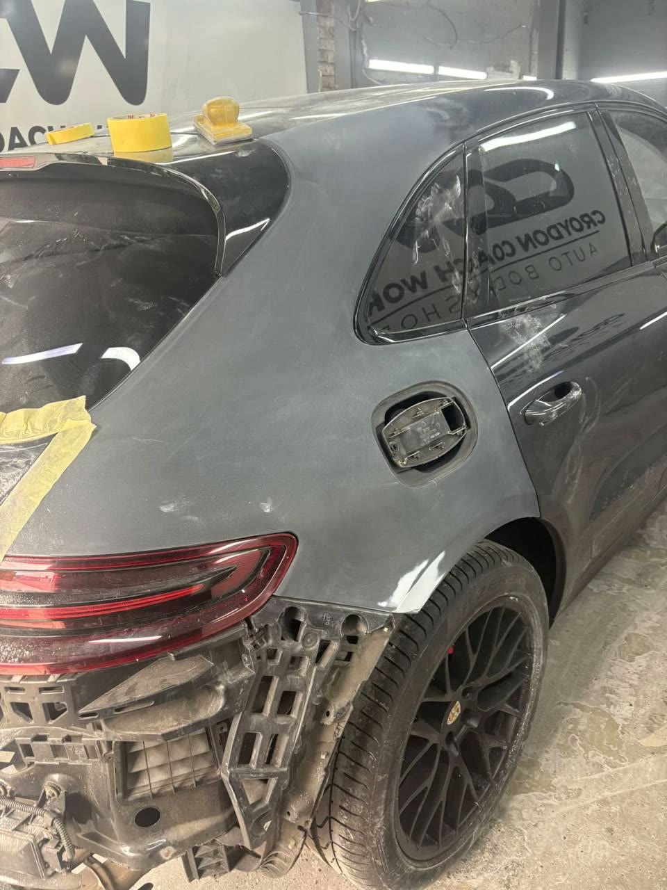 Grey Porsche Macan mid-repair at Croydon Coach Works, rear bumper removed and the rear quarter panel sanded back ready for paint