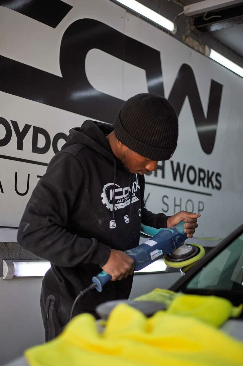 Technician machine-polishing a car in front of the Croydon Coach Works sign