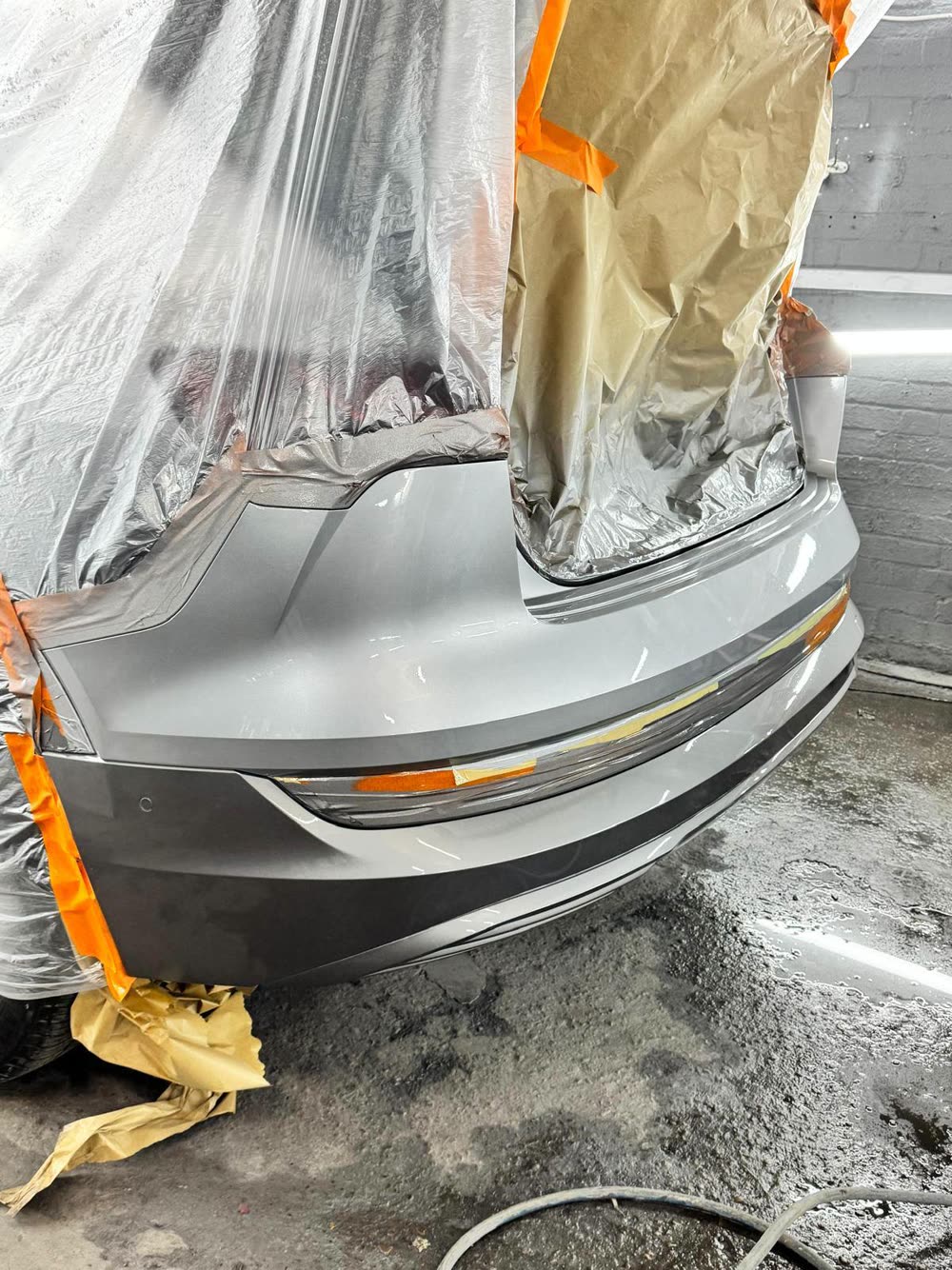 Silver rear bumper freshly painted with the rest of the car masked off