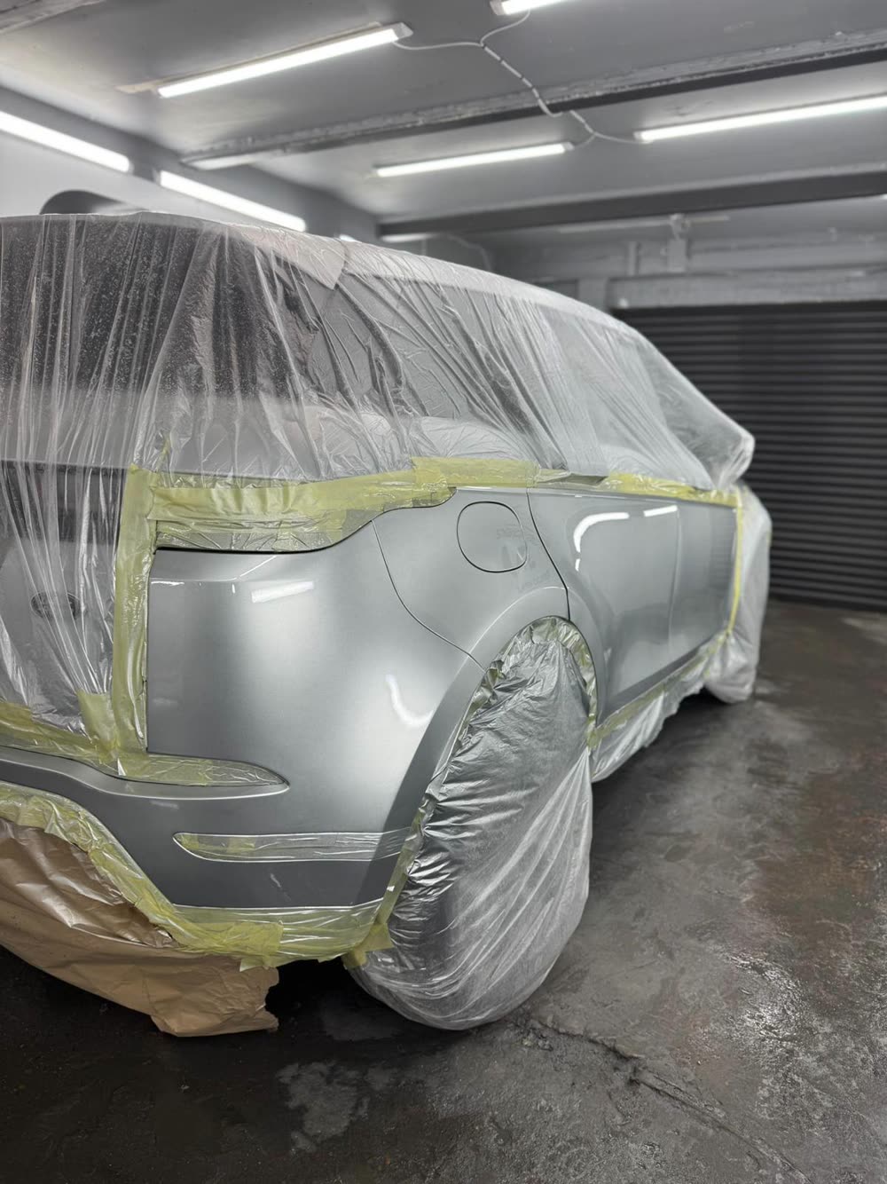 Silver Range Rover masked up in the booth with the rear quarter panel freshly painted